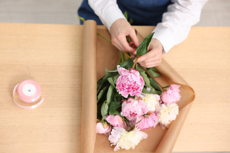 Florist making bouquet of peonies at wooden table, above viewの写真素材