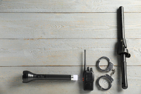 Different police equipment on gray wooden table, flat lay. Space for text