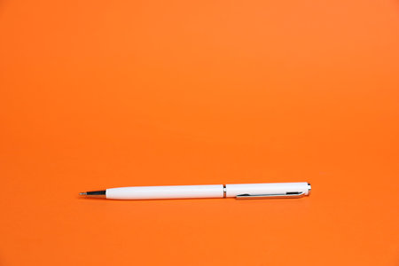 One white pen on orange background, space for textの写真素材