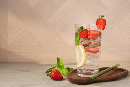 Tasty refreshing drink with strawberries, lemon and mint on wooden table, space for textの写真素材