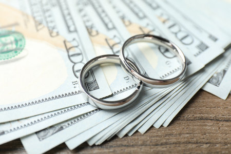 Silver wedding rings and dollar banknotes on wooden table, closeupの写真素材