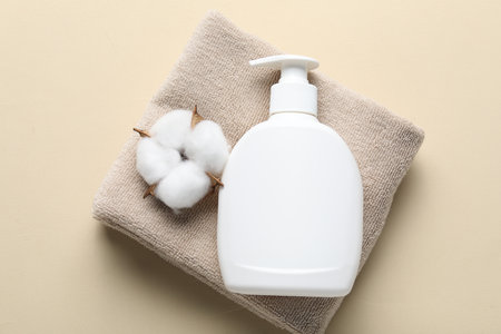 Bottle of liquid soap, cotton flower and towel on beige background, top viewの写真素材