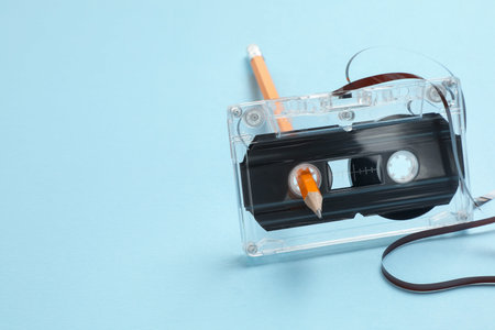 Rewinding audio cassette with pencil on light blue background, closeup. Space for textの写真素材