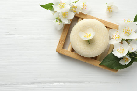 Soap bar and jasmine flowers on white wooden table, flat lay. Space for textの写真素材