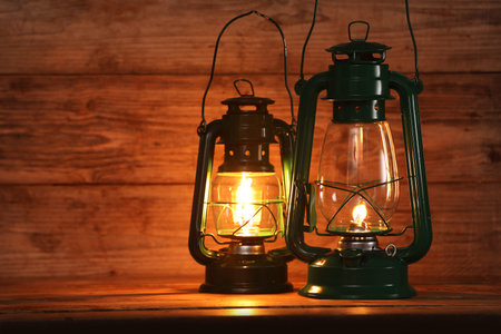 Vintage kerosene lanterns on wooden table, space for textの写真素材