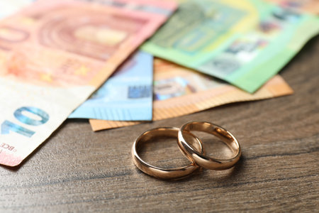 Gold wedding rings and euro banknotes on wooden table, closeupの写真素材