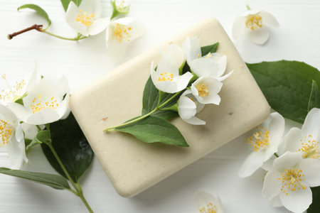 Soap bar and jasmine flowers on white wooden table, flat layの写真素材