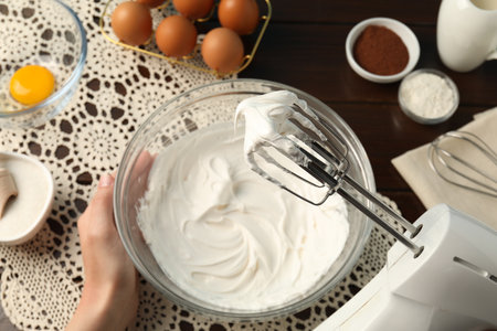 Woman whisking cream with hand mixer at table, top viewの写真素材