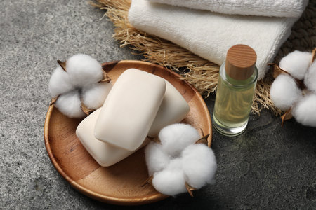 Soap bars, cosmetic product, cotton flowers and towels on gray table, above viewの写真素材