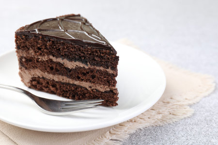 Piece of delicious chocolate cake and fork on gray table, closeup