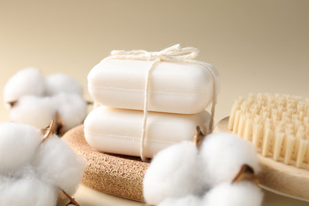 White soap bars, brush and cotton flowers on beige background, closeupの写真素材