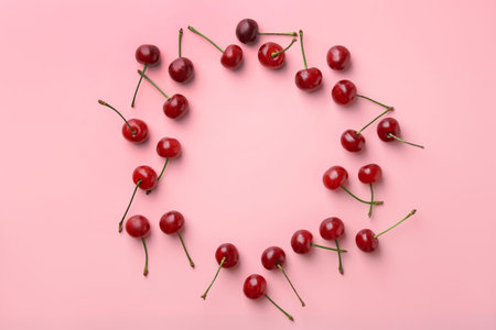 Frame of fresh ripe cherries on pink background, flat lay. Space for textの写真素材