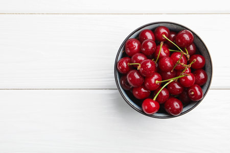 Wet ripe cherries on white wooden table, top view. Space for textの写真素材