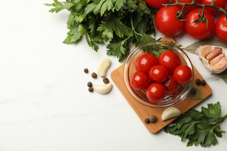 Tasty pickled tomatoes, parsley and spices on white table, flat lay. Space for textの写真素材