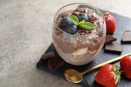Delicious chocolate pudding with chia seeds, strawberries and blueberries in glass on light gray table, closeup. Space for textの写真素材