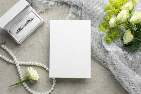 Wedding invitation card, silver rings and flowers on gray textured table, flat layの写真素材