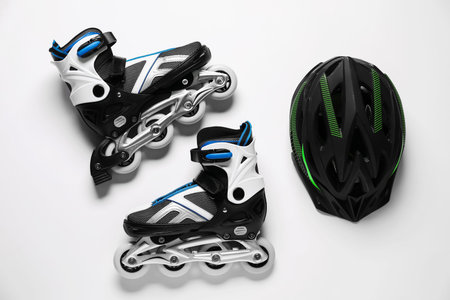 Pair of roller skates and helmet on white background, top view