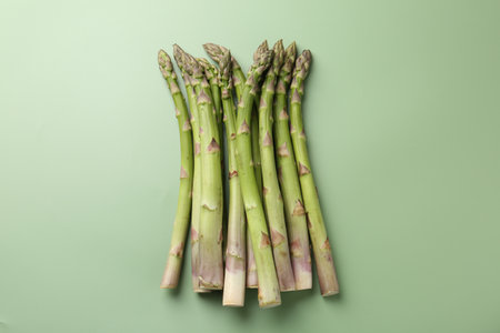 Fresh ripe raw asparagus on green background, flat layの写真素材