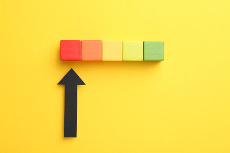 Maximum. Colorful cubes and arrow pointing at red one on yellow background, flat layの写真素材