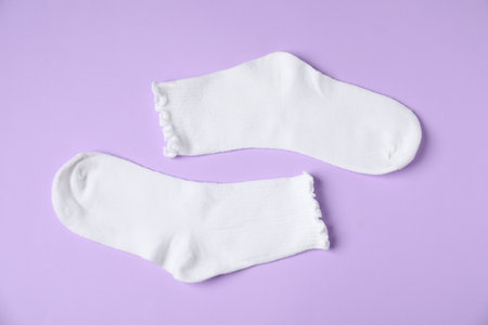 Pair of comfortable white socks on violet background, top viewの写真素材