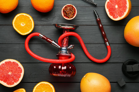 Hookah, coal and fresh fruits on black wooden table, flat lay