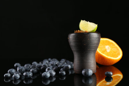 Hookah bowl with smoke and fruits on black table, closeup. Space for textの写真素材