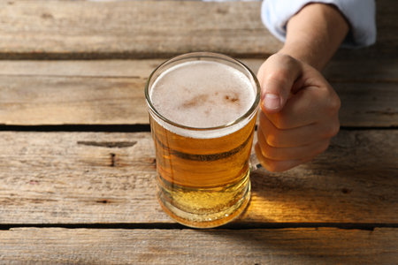 Man with glass mug of beer at wooden table, closeupの写真素材