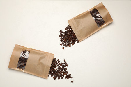 Zipper stand-up pouches and coffee beans on white table, flat lay. Mockup for designの写真素材