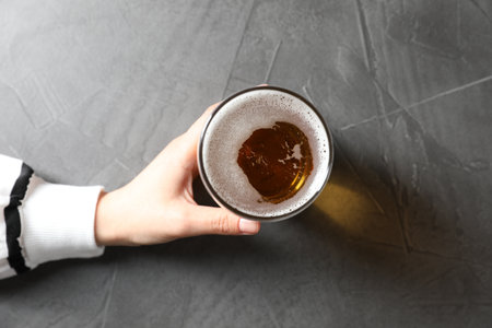 Woman with glass of beer at gray table, top viewの写真素材