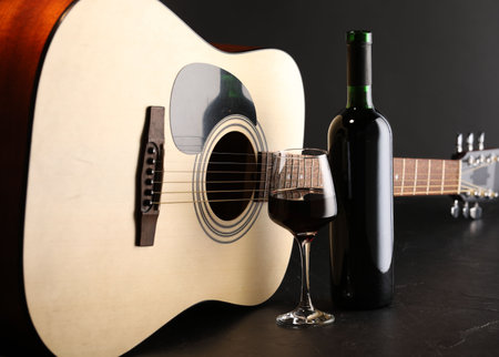 Acoustic guitar and red wine on black table, closeupの写真素材