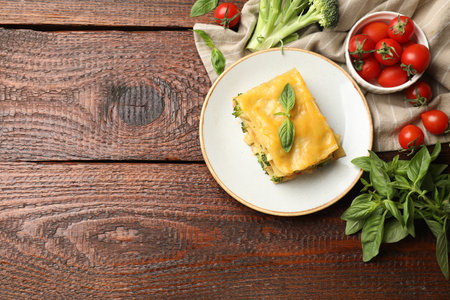 Piece of tasty vegetarian lasagna and ingredients on wooden table, flat lay. Space for textの写真素材