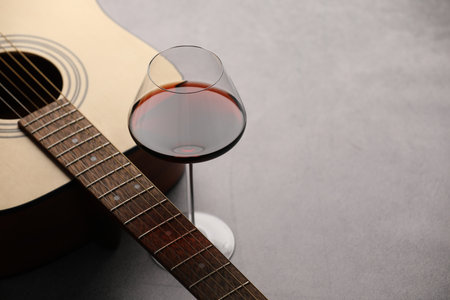 Acoustic guitar and red wine on gray table, closeup. Space for textの写真素材