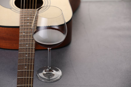 Acoustic guitar and red wine on gray table, closeup. Space for textの写真素材