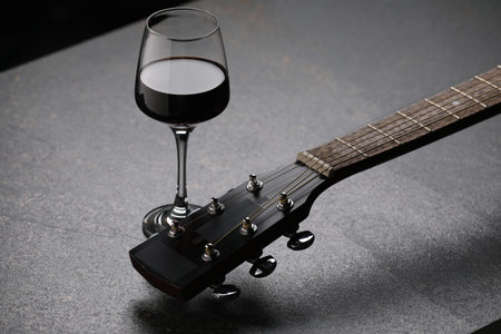 Acoustic guitar and red wine on black table, closeupの写真素材