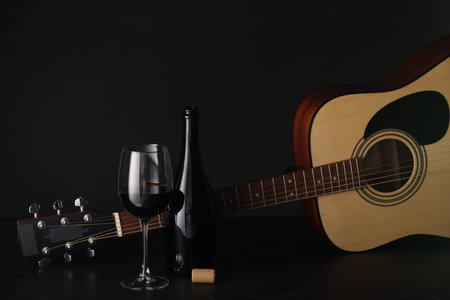 Acoustic guitar and red wine on black table, closeup. Space for textの写真素材