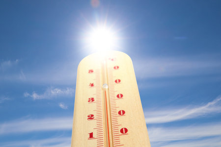 High temperature on thermometer against blue sky on sunny day. Summer weatherの写真素材