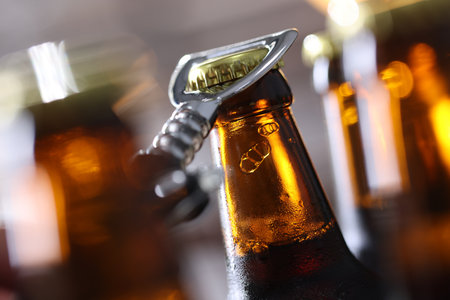 Opening bottle of beer on blurred gray background, closeupの写真素材