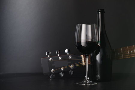 Acoustic guitar and red wine on black table, closeup. Space for textの写真素材