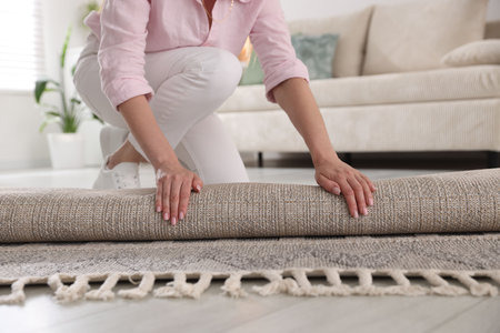 Woman putting new rug on floor at home, closeupのeditorial素材