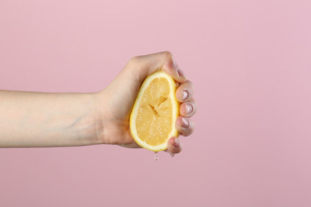 Woman squeezing lemon on pink background, closeupの写真素材