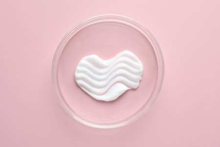 Cosmetic product in Petri dish on pink background, top view