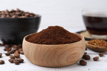 Instant coffee powder in bowl and beans on white wooden table, closeupの写真素材