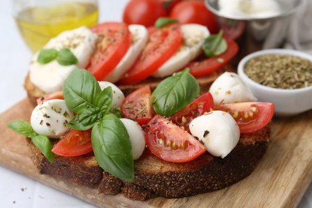Tasty sandwiches with mozzarella cheese, tomatoes, basil and spices on light table, closeupの写真素材