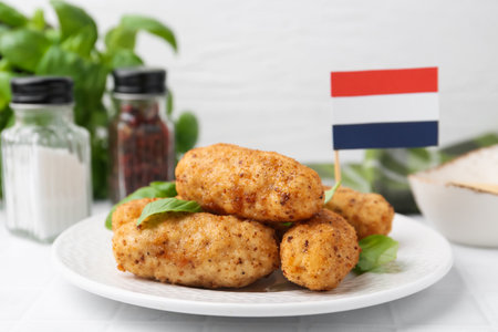 Tasty fried croquettes, basil and flag of the Netherlands on white tiled table, closeupの写真素材