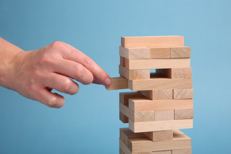 Lviv, Ukraine - December 04, 2023: Woman playing Jenga on light blue background, closeupの写真素材
