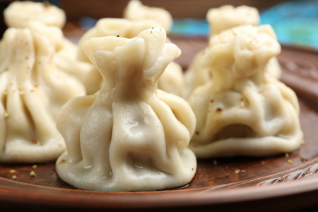 Many delicious khinkali on plate, closeup view