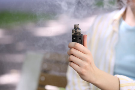 Young woman with electronic smoking device outdoors, closeup. Space for textの写真素材