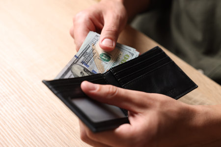 Man counting money at wooden table, closeup