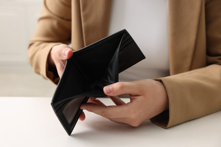 Woman with empty wallet at white table, closeupの写真素材