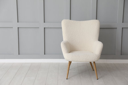 Comfortable beige armchair near light gray wall indoors, space for textの写真素材
